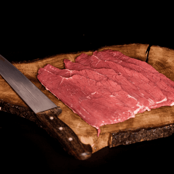 Carne de res magra en tabla de madera, preparación para cocinar.